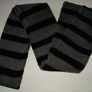 May include: A gray and black striped knitted scarf. The scarf is made of a soft, warm material and is perfect for keeping you warm in the winter.
