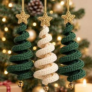 May include: Three hanging ornaments shaped like spiral Christmas trees, two in dark green and one in cream. Each ornament features a crocheted star at the top, a gold hanging cord, and a small gold jingle bell attached to the bottom point.