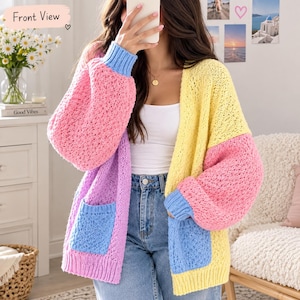 May include: A color-blocked open-front cardigan featuring a chunky knit texture. The garment displays panels of pastel yellow, pink, purple, and blue, with two front patch pockets and long sleeves finished with ribbed blue cuffs.