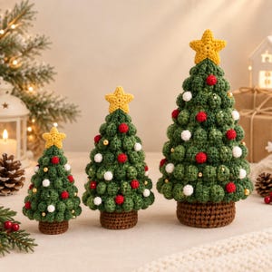 May include: Three cone-shaped Christmas trees made of green crocheted yarn, each featuring a yellow star topper, a brown crocheted base, and small red, white, and gold spherical ornaments attached throughout the textured green surface.