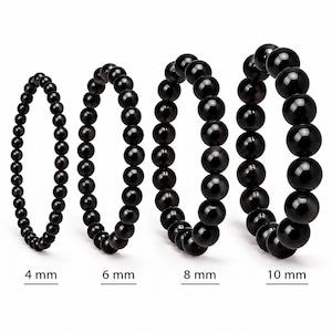 Peut inclure: Quatre bracelets circulaires composés de perles noires polies disposées par taille croissante. Les bracelets sont étiquetés avec leurs diamètres de perle respectifs de 4 mm, 6 mm, 8 mm et 10 mm, montrant l'échelle des perles de chaque pièce.