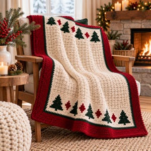 May include: A cream-colored crocheted blanket featuring a repeating pattern of dark green pine trees and small red diamond shapes. The blanket is bordered by a wide, solid red crocheted edge and a thin dark green trim along the inner border.