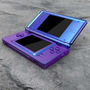 May include: A handheld dual-screen video game console featuring a metallic purple and blue gradient finish. The device is open, revealing two black screens, a directional pad, four action buttons, and small circular buttons labeled Select and Start.