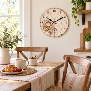 Könnte beinhalten: Eine runde Wanduhr mit cremefarbenem Zifferblatt, schwarzen Ziffern, schwarzen Zeigern und einem zentralen Motiv eines Latte Macchiato in einer weißen Tasse mit Latte Art, zwei kleinen Keksen und verstreuten Kaffeebohnen auf einem Fliesenmuster.