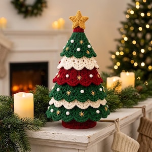 Könnte beinhalten: Eine gehäkelte Weihnachtsbaumdekoration mit abwechselnden Schichten aus dunkelgrünem, cremefarbenem und tiefrotem, gewelltem Garn. Der Baum ist mit einem gelben Stern gekrönt und mit kleinen weißen Bommeln und goldenen Sternstickereien verziert.
