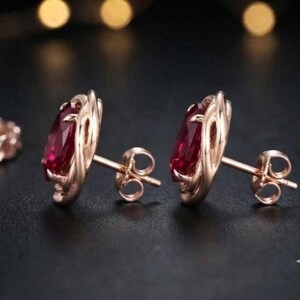 Peut inclure: Une paire de boucles d'oreilles &agrave; clous en or rose avec des pierres pr&eacute;cieuses rouge fonc&eacute; taille ovale, serties dans une monture en m&eacute;tal textur&eacute; et torsad&eacute;. Chaque boucle comprend une tige et un fermoir papillon assortis.