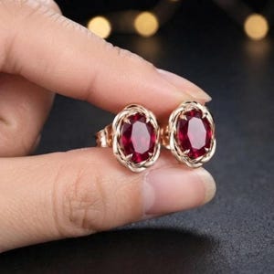 Peut inclure: Une paire de boucles d'oreilles &agrave; clous avec des pierres pr&eacute;cieuses rouge fonc&eacute; de taille ovale, serties dans une monture en m&eacute;tal or rose torsad&eacute;. Les boucles d'oreilles pr&eacute;sentent une finition polie et un fermoir &agrave; tige s&eacute;curis&eacute;.