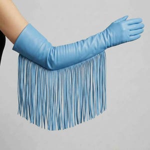 May include: A light blue opera-length glove made of smooth material, extending past the elbow. The glove features a long, dense fringe detail that hangs from the forearm section, creating a layered effect with thin, vertical strips of matching blue.