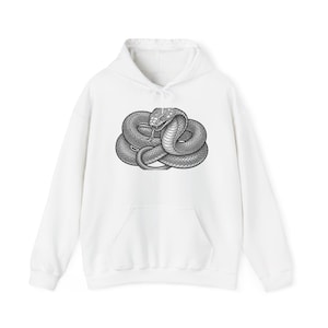 Könnte beinhalten: Ein weißer Kapuzenpullover mit einer schwarz-weißen grafischen Illustration einer zusammengerollten Kobra auf der Brust. Der Hoodie verfügt über lange Ärmel, eine Kängurutasche auf der Vorderseite und weiße Kordelzüge an der Kapuze.