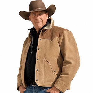 May include: A tan suede jacket with a cream-colored shearling collar, featuring a button-front closure and dark brown suede shoulder panels. The jacket is worn over a black shirt and blue jeans, paired with a brown felt cowboy hat.