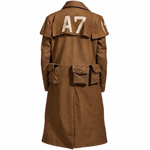 May include: A brown long coat featuring a wide back yoke with the white text A7 printed on it. The garment includes a collar, long sleeves, and three distinct flap pockets positioned across the lower back area, each secured with a small metal button.