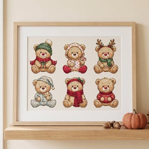 May include: A framed cross-stitch pattern featuring six light brown teddy bears in various winter outfits, including hats, scarves, and pyjamas, arranged in two rows of three on a light cream background within a light wood frame.