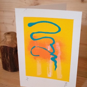 Könnte beinhalten: Grußkarte mit abstraktem Design. Die Karte hat einen gelben Hintergrund mit einem orangefarbenen Farbverlauf und türkisfarbenen, geschwungenen Linien. Weiße vertikale Pinselstriche sind ebenfalls vorhanden. Die Karte liegt auf einer Holzoberfläche.
