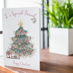 Pu&ograve; includere: Un biglietto di Natale con un'illustrazione ad acquerello di un albero di Natale decorato. Il biglietto recita "To a Special Friend" e "Happy Christmas" in uno script bordeaux. L'albero &egrave; adornato con ornamenti e fiocchi.