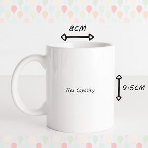 May include: A white ceramic mug with a handle, 3.1 inches in diameter and 3.7 inches tall, with an 11oz capacity. The mug has the text "11oz Capacity" printed on the side. The background features a pattern of colorful balloons.