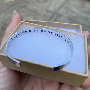 Puede incluir: Un brazalete de plata con la inscripci&oacute;n "Yo no ser&iacute;a yo sin ti". El brazalete est&aacute; en una peque&ntilde;a caja blanca.