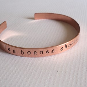 Puede incluir: Una pulsera de cobre con la inscripci&oacute;n "les bonnes choses" en cursiva.