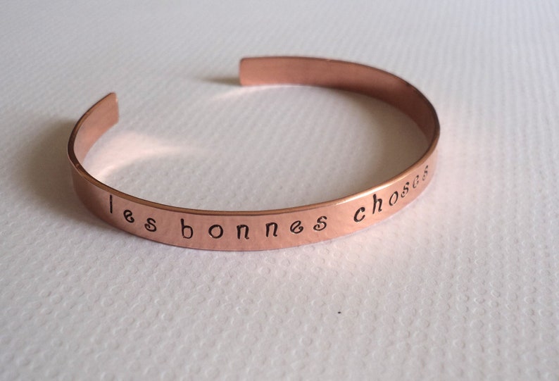 Puede incluir: Una pulsera de cobre con la inscripci&oacute;n "les bonnes choses" en cursiva.