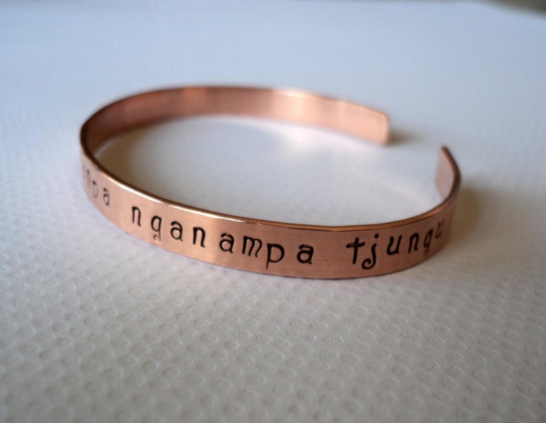 Puede incluir: Una pulsera de cobre con la inscripci&oacute;n "nga nampa tjunga" grabada.