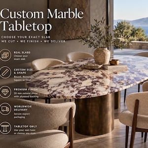 Op de afbeelding: Een ovaal marmeren tafelblad met een gepolijst oppervlak met dieppaarse en witte aders. Het tafelblad rust op een cilindrische, bronskleurige voet. De tekst op de afbeelding luidt: Custom Marble Tabletop, Choose Your Exact Slab, We Cut, We Finish, We Deliver, Real Slabs, Custom Size & Shape, Premium Finish 20 mm natural stone with plywood backing, Worldwide Delivery, Tabletop Only.