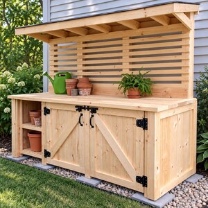 May include: A light-colored wooden potting bench featuring a slatted back panel, a roof overhang, and two cabinet doors with black metal hinges and handles. The bench includes open shelving on the left side, holding several terracotta pots.