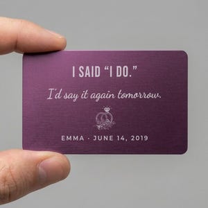 May include: A rectangular purple metal card featuring the white text I SAID "I DO." and I'd say it again tomorrow. Below the text is a line drawing of two interlocking rings with a diamond, followed by the name EMMA and the date JUNE 14, 2019.