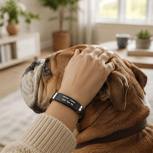 May include: A black metal bracelet with silver-toned accents featuring the engraved text "Never Alone. God Has Me." The bracelet has a smooth, rectangular center plate and a flexible band design worn on a wrist.