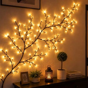 May include: A wall-mounted decorative branch light fixture featuring numerous small, warm-toned LED bulbs attached to dark, slender, branching stems that extend across the wall in a natural, organic, tree-like formation.