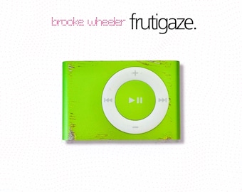 May include: A lime green digital music player with a white circular control pad featuring play, pause, and skip icons. The text "brooke wheeler" and "frutigaze." appears in black above the device against a white background.