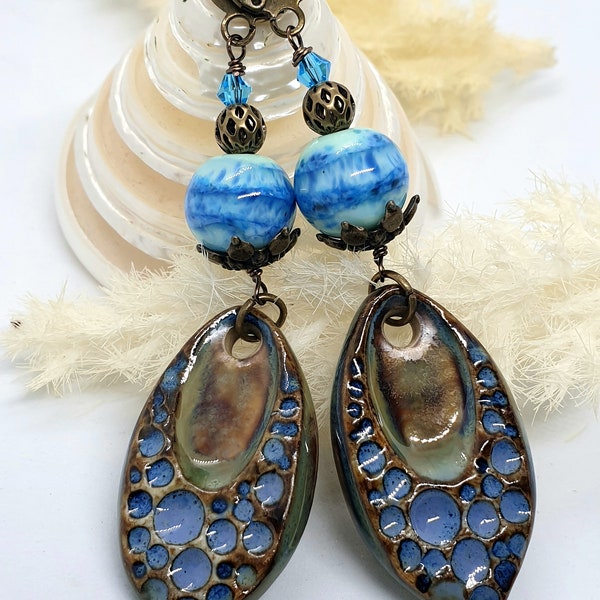 Jolies boucles d'oreilles avec breloques en céramique  et perles en verre filé tons bleus.