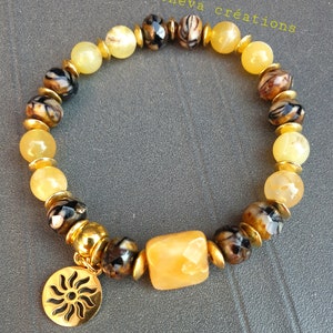 May include: A gold bracelet with yellow and brown beads and a gold sun charm. The bracelet is made by passioneva creations.