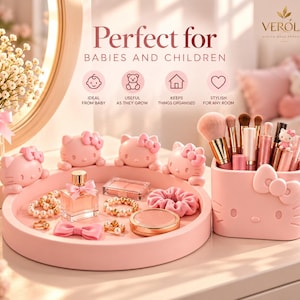 May include: A light pink circular vanity tray and a matching rectangular brush holder, both featuring Hello Kitty character motifs. The tray holds jewellery, a perfume bottle, and a compact, while the holder contains various makeup brushes.