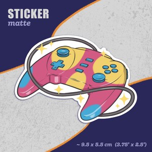 Puede incluir: Una pegatina mate con un mando de videojuego rosa y amarillo con un cable negro. El mando tiene un diseño azul y blanco y está rodeado de estrellas brillantes. La pegatina mide aproximadamente 9,5 x 5,5 cm (3,75 x 2,5 pulgadas).