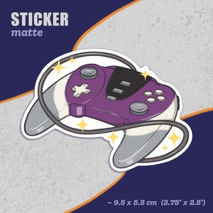May include: Purple and white video game controller sticker with a black cord. The sticker is matte and measures approximately 3.75 inches by 2.5 inches.