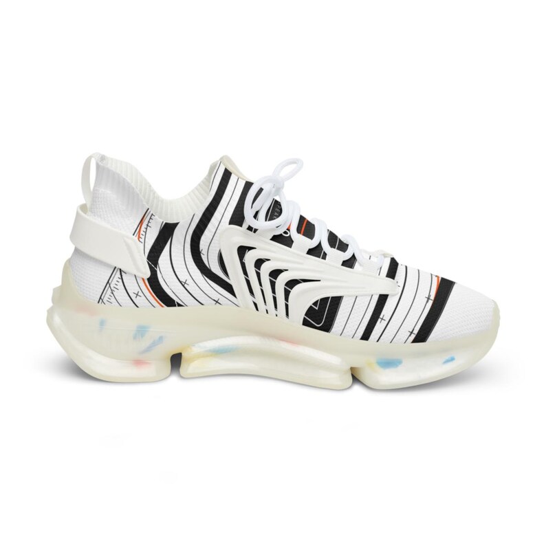 K&ouml;nnte beinhalten: Ein wei&szlig;er Sneaker mit schwarzen vertikalen und geschwungenen Linienmustern, orangefarbenen Akzenten und wei&szlig;en Schn&uuml;rsenkeln. Der Schuh hat eine durchscheinende, klobige Sohle mit dezenten bunten Sprenkeln und einen wei&szlig;en Fersenriemen.