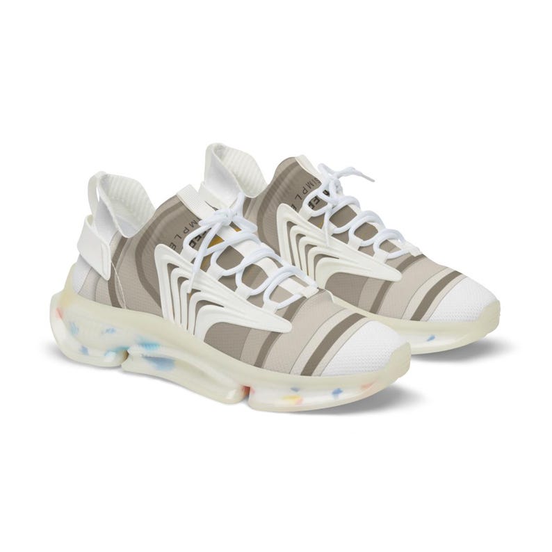 Puede incluir: Un par de zapatillas deportivas con parte superior a rayas beige y blancas, cordones blancos y una superposici&oacute;n estructural blanca. La suela transl&uacute;cida incluye motas multicolores y la palabra SIMPLE est&aacute; impresa en la leng&uuml;eta.