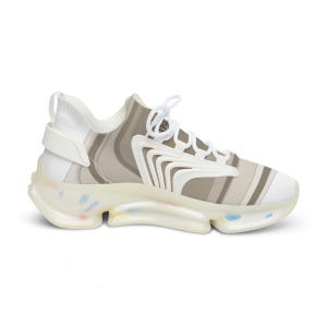 Puede incluir: Una zapatilla baja con parte superior a rayas blancas y beige y cierre de cordones blanco. El calzado incluye un revestimiento estructural blanco en el lateral y una suela gruesa y transl&uacute;cida con motas multicolores incrustadas.