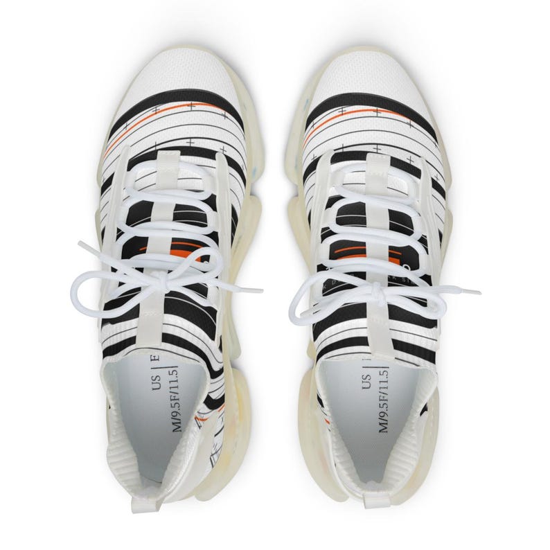 K&ouml;nnte beinhalten: Ein Paar wei&szlig;e Sneaker mit einem schwarzen und orangefarbenen linearen Grafikmuster und Fadenkreuzdetails. Die Schuhe haben wei&szlig;e Schn&uuml;rsenkel, eine durchscheinende Sohle und ein Innenetikett mit der Aufschrift US M 9.5 F 11.5.