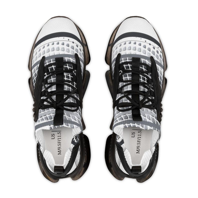 May include: A pair of athletic trainers featuring a white and grey grid pattern on the upper, black laces, and a translucent dark grey sole. The interior insole is clearly printed with the text US M/9.5 F/11.5, indicating the shoe size.