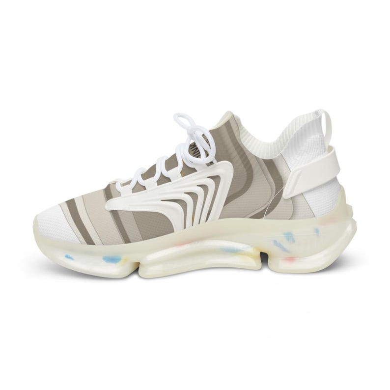 Puede incluir: Una zapatilla baja con un patr&oacute;n de rayas blancas y beige en la parte superior, cordones blancos y una superposici&oacute;n estructural blanca. La suela transl&uacute;cida incluye peque&ntilde;as motas multicolores en la base y el tal&oacute;n.