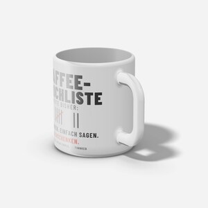 以下が含まれることがあります： KAFFEE-STRICHLISTE、HEUTE BISHERなどのドイツ語のテキストと正の字のグラフィックが黒と赤でプリントされた白いセラミック製のマグカップ。円筒形の本体と右側に湾曲したハンドルが付いています。