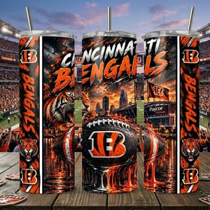 Könnte beinhalten: Ein zylindrischer Becher mit Strohhalm im Design der Cincinnati Bengals. Das Motiv zeigt einen Tiger, einen Football mit Teamlogo, eine Stadionkulisse sowie den Schriftzug Cincinnati Bengals in den Farben Orange und Schwarz.