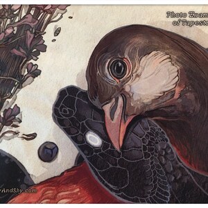 May include: A tapestry featuring a close-up of a bird's head with a black and white snake wrapped around its neck. The bird has a brown head with a white beak and a black eye. The snake has a black and white pattern. The background is a light brown color with a bouquet of purple flowers in the upper left corner. The text "Photo Example of Tapestries" is in the upper right corner.