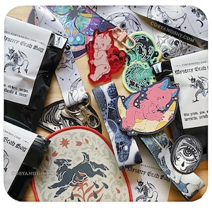 Può includere: Una collezione di merchandising di COEYANDSHY.COM, tra cui una mystery grab bag, adesivi, toppe, cordini e braccialetti. Gli articoli presentano illustrazioni di un diavolo, un gatto rosa che dorme e altri disegni celesti e gotici. La tavolozza dei colori include nero, bianco, rosso e blu.