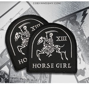 May include: Two black embroidered patches with white stitching. The patches feature a skeleton riding a horse with a scythe. The text "HORSE GIRL" and the Roman numeral "XIII" are on the patches.