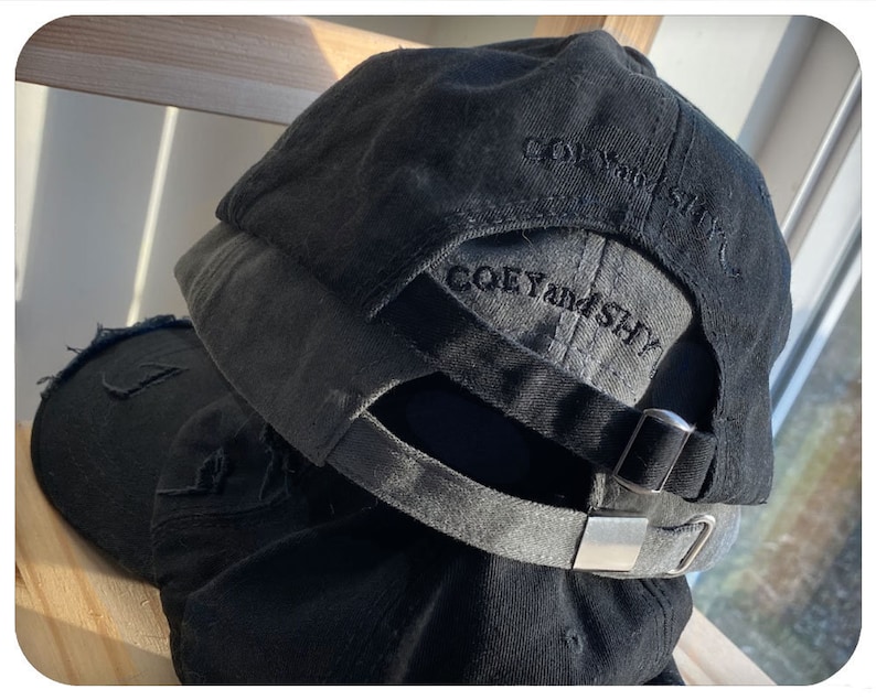 May include: Black baseball cap with a distressed look and the text "COEY and SHY" embroidered on the back.