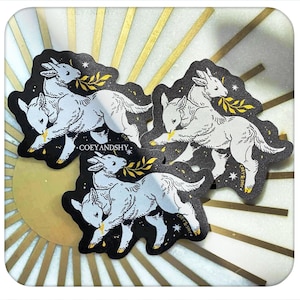 Puede incluir: Tres pegatinas con una ilustración de cabra gris claro con una ramita de hojas, sobre un fondo negro con estrellas. Las pegatinas tienen una forma única y el texto "COEYANDSHY" es visible.