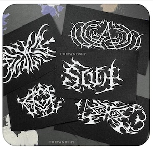 May include: Several black fabric patches with white tribal designs and text. The patches display diverse abstract patterns and stylized lettering. The text "COEYANDSHY" is visible on some patches.