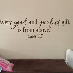 May include: A brown wall with a white bed frame and a brown mattress. The wall has a vinyl decal with the text "Every good and perfect gift is from above. James 1:17"