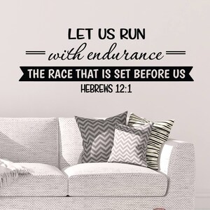 May include: Black and white wall decal with the quote "Let us run with endurance = The race that is set before us = Hebrews 12:1". The decal is displayed on a white wall above a white couch with gray and white patterned pillows.